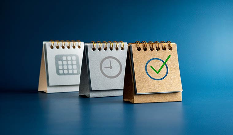 Checked icon, Time and date symbol on three desk calendar covers standing isolated on blue background - scheduling concept