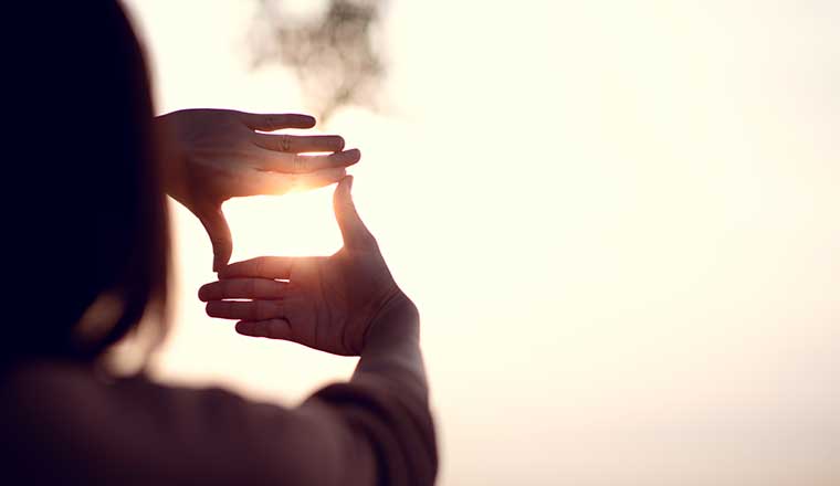 Vision concept with persons hands making frame gesture with sunset
