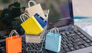 Five paper shopping bags and a shopping cart on a laptop keyboard.