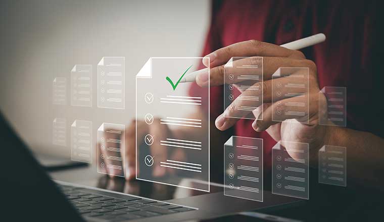 Person on laptop with virtual documents with checkmarks