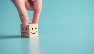 Close up customer hand choose smiley face and sad face icon on wood cube