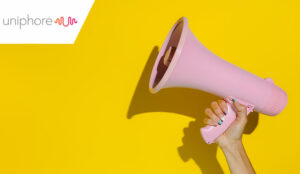 A hand holding a pink megaphone isolated on a yellow background