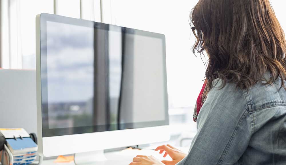 Rear view of person using desktop computer