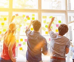 Workshop with people putting sticky notes on window