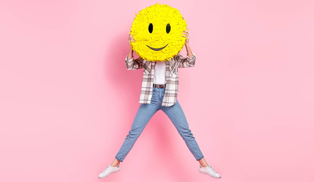 person holding a smiley face over her face