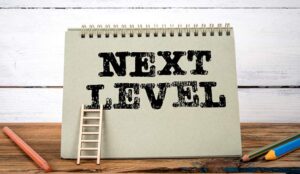 Next level written on notepad with mini ladder