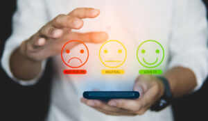 Good CX concept, with person on phone choosing happy face icon for positive experience