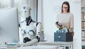 Disappointed businesswoman packing her belongings and leaving the office with an AI robot sat at the desk on the computer