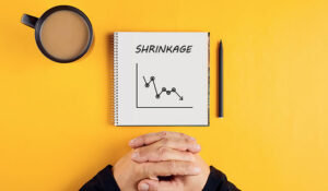 Hands of a businessman and a spiral notebook with the word 'shrinkage' written on it