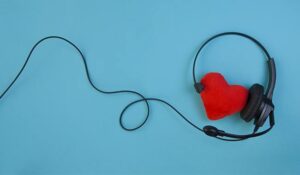 A red heart with a call centre headset on it - on a blue background