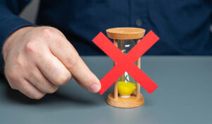 A man holds a red cross on top of an hourglass.
