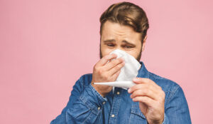 Sick person with a tissue looking at thermometer