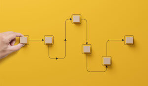 Hand holding wooden cube block arranging processing management on yellow background