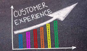 CUSTOMER EXPERIENCE written with chalk on tarmac over colourful graph and rising arrow