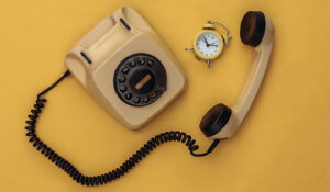 Old fashioned telephone with a clock on a yellow background