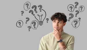 Thoughtful young man and drawn question marks on grey background with space for text