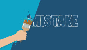 Hiding mistake concept with person painting over the word mistake