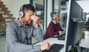Call centre agent with hand on head looking exhausted and sad