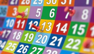 A colourful month of calendar dates with a few red pins stuck in various dates