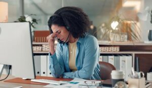 Person in headset sat at desk with headache