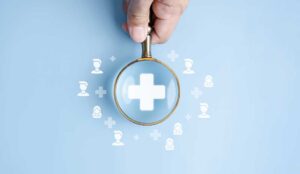 Hand holding magnifier with plus sign inside and healthcare medical icon surrounded by people icons