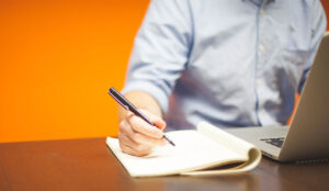 ACW concept with person on laptop making notes