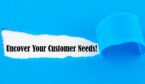 Text Uncover Your Customer Needs appearing behind torn paper.
