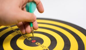 Person cheating to hit target concept with hand placing dart in center of board