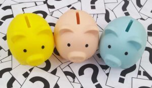 Top view of three piggy banks on question marks