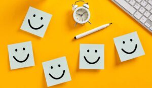 Customer experience concept with a clock and sticky notes with smiley faces