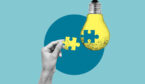 Idea and building concept with a hand putting a missing piece of a lightbulb in place