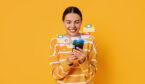 Happy woman using mobile phone to use self service on orange background with icons around it