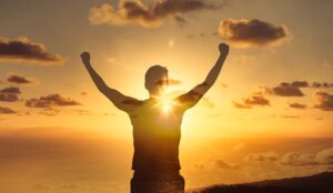 Empowerment concept with a person raising their arms at sunset