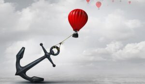 Held back metaphor as a large anchor holding an air balloon and restricting movement