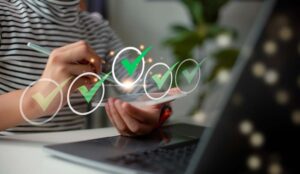 Person with laptop and phone with digital checkmarks - quality concept